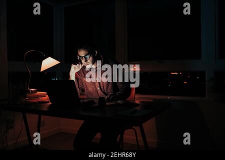 Caucasian male student working late at night stressed meeting deadlines sitting at home workspace Stock Photo