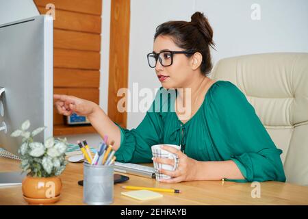 Businesswoman pointing at computer screen Stock Photo