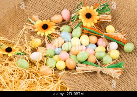 Easter colorful eggs and flowers on brown burlap background. Stock Photo