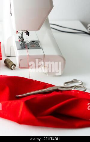 Modern sewing machine with red and gray fabric, thread and scissors, cutting and sewing at home, home leisure and hobby Stock Photo