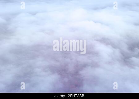 Art texture of the Light magenta misty rain clouds is the view from the cockpit. Misty layer of atmosphere over a rainy city - view from the plane Stock Photo
