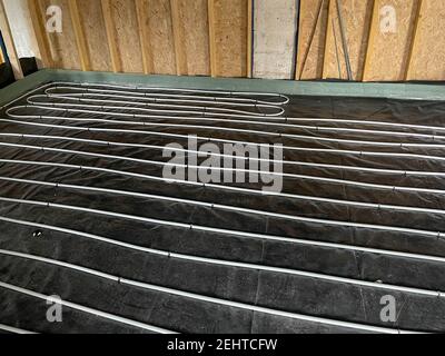 Underfloor Heating Pipes Laid on Top of Black Plastic Sheets on the Floor of a Building Conversion in Rural Devon, England, UK Stock Photo