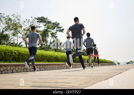 rear view of group of young asian adults running training outdoors in park Stock Photo