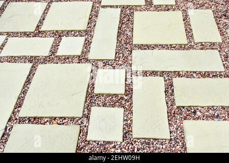 A lovely patio area with light coloured stone slabs and gravel with pinkish tones in an asymmetric pattern Stock Photo