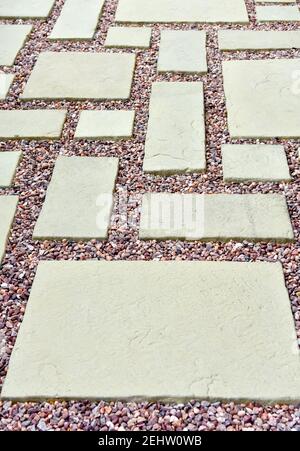 A lovely patio area with light coloured stone slabs and gravel with pinkish tones in an asymmetric pattern Stock Photo