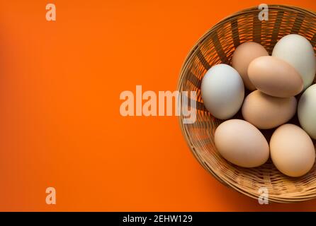 Organic chicken eggs in wicker basket on red background with copy space. Stock Photo
