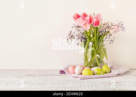 Spring Easter composition with bouquet of pink tulips and painted eggs on light background. Space for text. Stock Photo