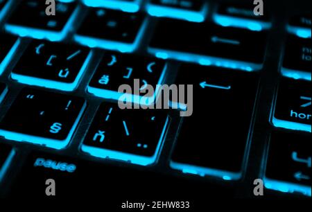Modern blue iluminated backlit keyboard.Blue backlight, backlit on laptop or keyborad computer of gaming in the dark.Paused game. Cyber Attack concept. Stock Photo