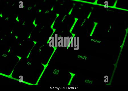 Modern green iluminated backlit keyboard. Green backlight, backlit on keyborad computer of gaming in the dark. Cyber Attack, hacking concept. Stock Photo