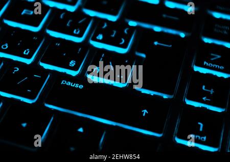 Modern blue iluminated backlit keyboard.Blue backlight, backlit on laptop or keyborad computer of gaming in the dark.Paused game. Cyber Attack concept. Stock Photo
