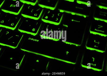 Modern green iluminated backlit keyboard. Green backlight, backlit on laptop or keyborad computer of gaming in the dark. Paused game concept. Stock Photo