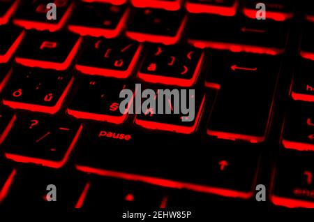 Red iluminated backlit keyboard, on laptop or keyborad computer of gaming in the dark. Cyber Attack, hacking and Internet security concept. Stock Photo