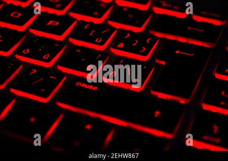 Red iluminated backlit keyboard, on laptop or keyborad computer of gaming in the dark. Cyber Attack, hacking and Internet security concept. Stock Photo
