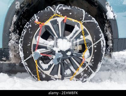 snow chains fitted on a car wheel in winter Stock Photo