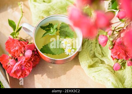 tea with petals of roses on a knitted cloth, romance love.Summer in the village, natural tea, breakfast outdoors Stock Photo