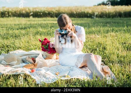 Field in daisies, a bouquet of flowers.French style romantic picnic setting. Woman in cotton dress.takes pictures, photographer , strawberries Stock Photo