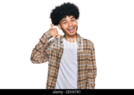 Young african american man with afro hair wearing casual clothes smiling doing phone gesture with hand and fingers like talking on the telephone. comm Stock Photo