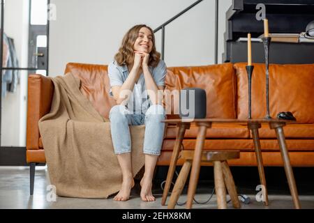 Woman listen to audio assistant column sitting on sofa Stock Photo