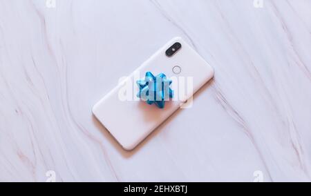 mobile phone gift wrapped with bow on white background Stock Photo