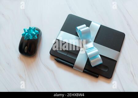 digital tablet and mouse wrapped with blue ribbons Stock Photo