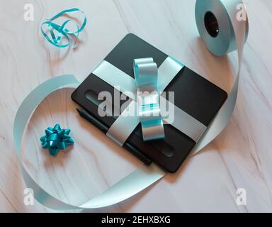 gift wrapped digital tablet with blue bow and gift ornaments Stock Photo