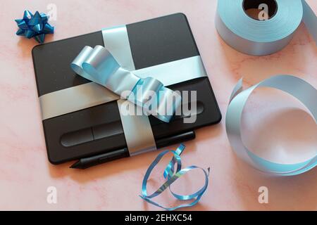 gift wrapped digital tablet with blue bow and gift ornaments Stock Photo