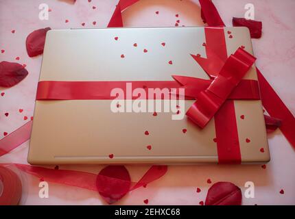 laptop wrapped with red gift bow with background ornaments Stock Photo