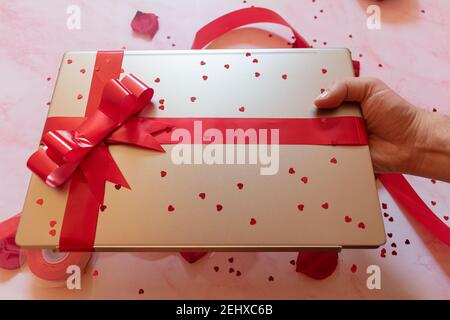 laptop wrapped with red gift bow with background ornaments Stock Photo