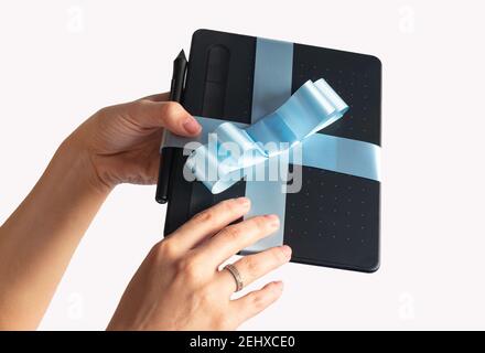 gift wrapped digital tablet with blue bow with hands delivering it Stock Photo