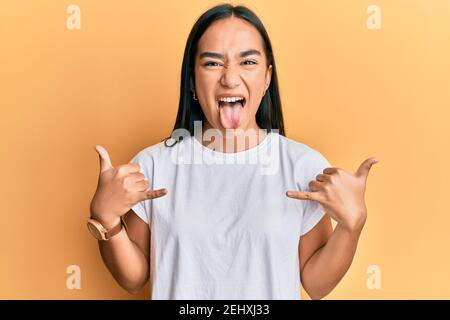 Young asian woman doing shaka sign with hands sticking tongue out happy with funny expression. Stock Photo