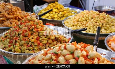 Exotic Oriental Asian sweet delicious desserts, unusual colorful traditional dishes on the counters of a bazar with street food. Evening food court in Stock Photo