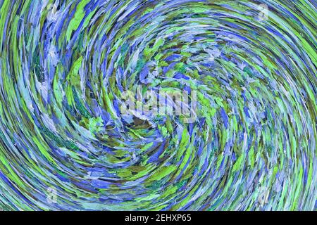 Abstract: Swirl or spiral of blue green white tinted Autumn leaves lying on green grass Stock Photo
