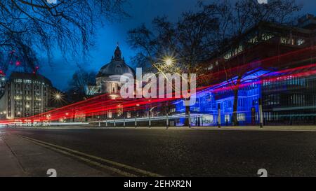 Light trails pass the Queen Elizabeth II Conference Centre and Methodist Central Hall at dusk in Westminster, London during lockdown. Stock Photo