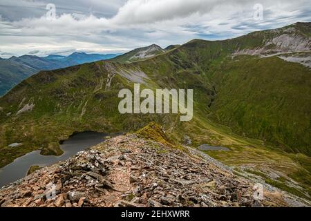 Scottish highlands mountain landscape. Peak of Sgurr Eilde Mor seen across the small lochan from the hiking trail in Mamores range, Scotland