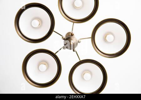 Bronze chandelier with five white glass lamp shades on a ceiling in a bedroom. Interior design. Stock Photo