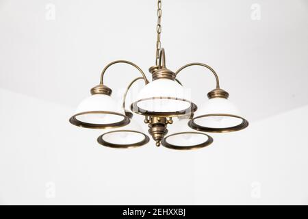 Bronze chandelier with five white glass lamp shades on a ceiling in a bedroom. Interior design. Stock Photo