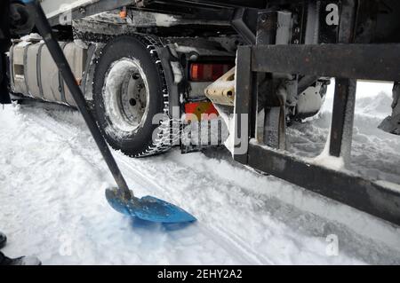 A heavy car got stuck in the snow on the road. Dig it out when looking for a shovel. Stock Photo