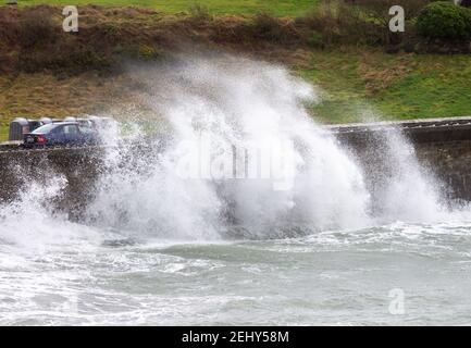 Winter Storm waves breaking over Sea Wall covering passing car. Stock Photo