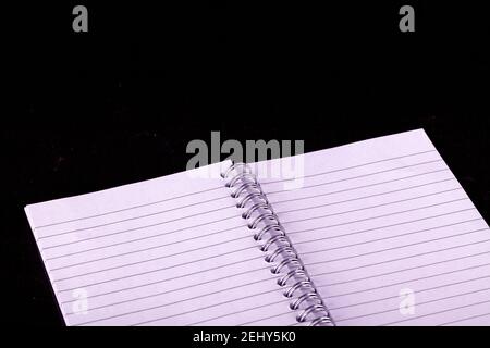 Opened A5 notepad with white lined pages and spiral bound with a black background Stock Photo