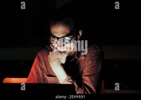 Close up caucasian male freelancer reading off laptop working late at night Stock Photo