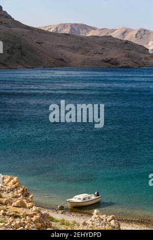 A Boat Docked in A Cove of a Rocky Beach in Island Pag and Sea in the Background Stock Photo