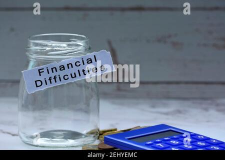 Glass jars with blurred multicurrency coins, calculator and text on white torn paper - Financial difficulties Stock Photo