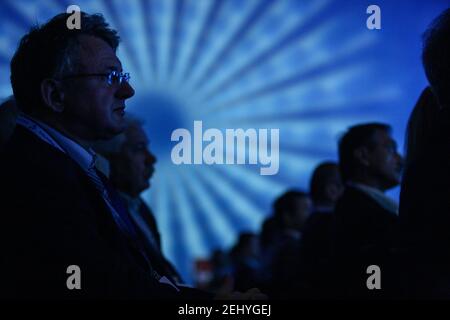 Men Sitting and Watching in a Row with Blue Blurry Circular Background Stock Photo
