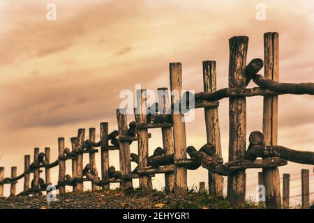 Old Wooden Fence Made From Trees and Branches Overlooking the Grey Skies Stock Photo