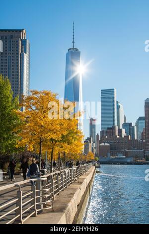 Lower Manhattan skyscraper stands behind the autumn leaf color trees along the Hudson River at New York City NY USA. Stock Photo