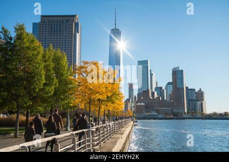 Lower Manhattan skyscraper stands behind the autumn leaf color trees along the Hudson River at New York City NY USA. Stock Photo