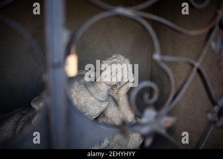 Statue and sculpture of female, woman and girl is hidden behind the bars. Figurine is contemplating and dreaming with closed eyes. Very shallow focus. Stock Photo