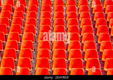 Rows of vibrant red chairs arranged in perfect alignment for an upcoming event at a modern venue Stock Photo