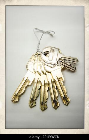 Keys arranged on a string showcasing various shapes and sizes against a plain background Stock Photo