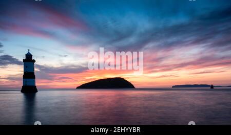 Sunrise at Penmon Point, Anglesey, Wales, United Kingdom. Penmon (Trwyn Du) lighthouse and Puffin Island.  Dramatic, colourful skiy and smooth sea. Stock Photo